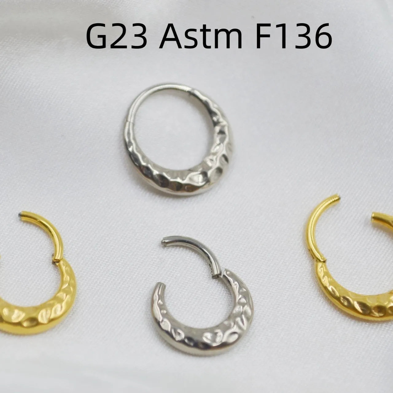 Titanium alloy concave-convex nose ring with carving detail in gold and silver anodised finishes.