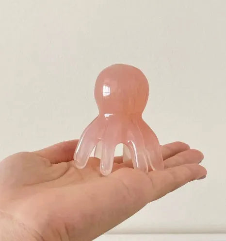 Small pink octopus-shaped periocular massage comb made from natural resin with storage bag