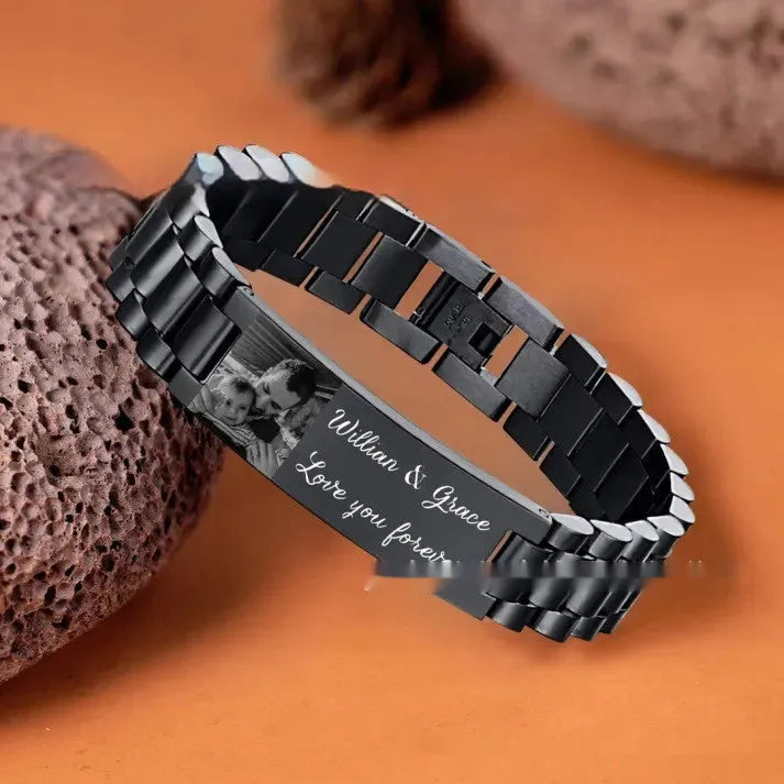 Titanium steel men's bracelet with curved heart shape and black lettering on a grey background.