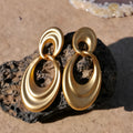 Plain gold coloured U-shaped double circle earrings with a French retro style on a copper background.