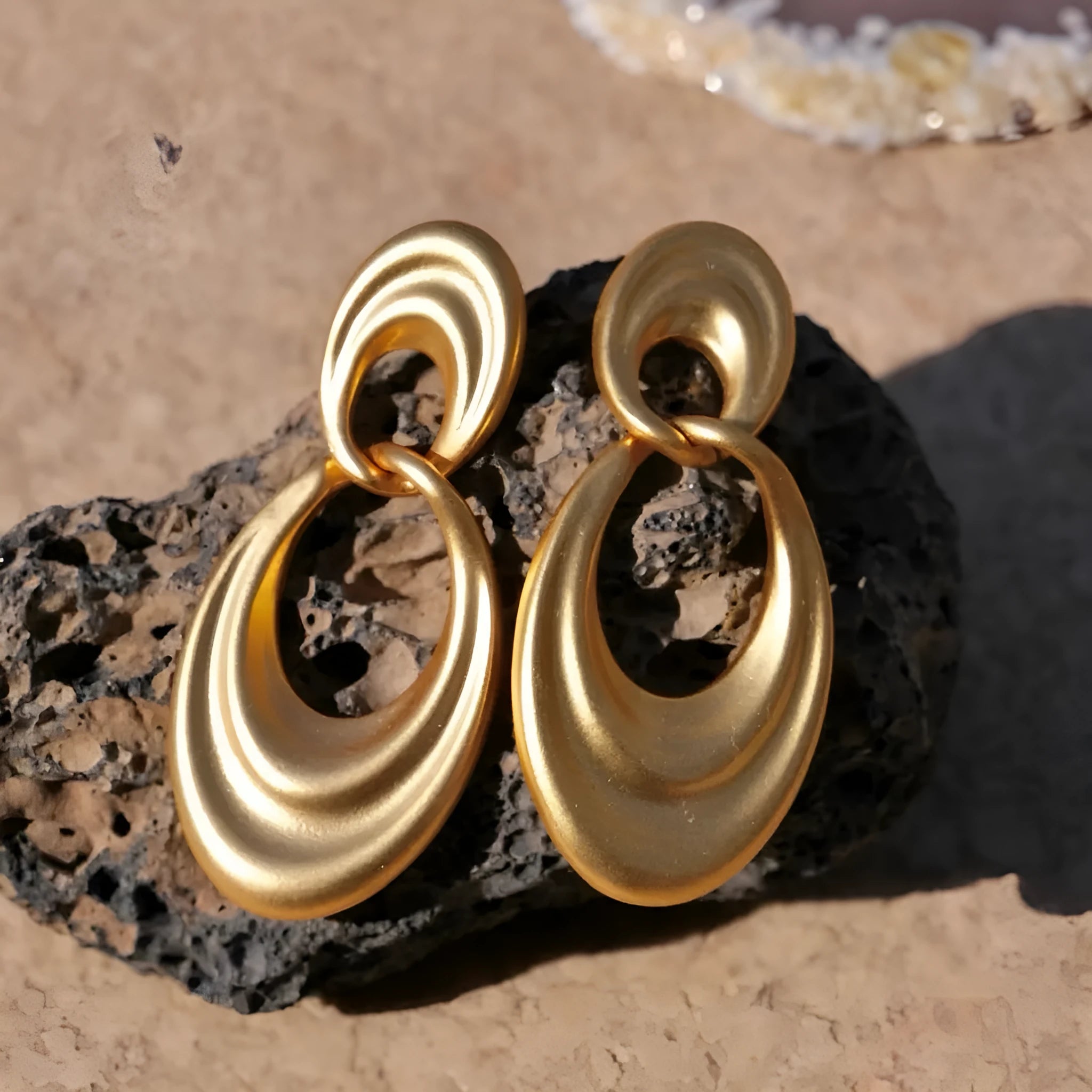 Plain gold coloured U-shaped double circle earrings with a French retro style on a copper background.