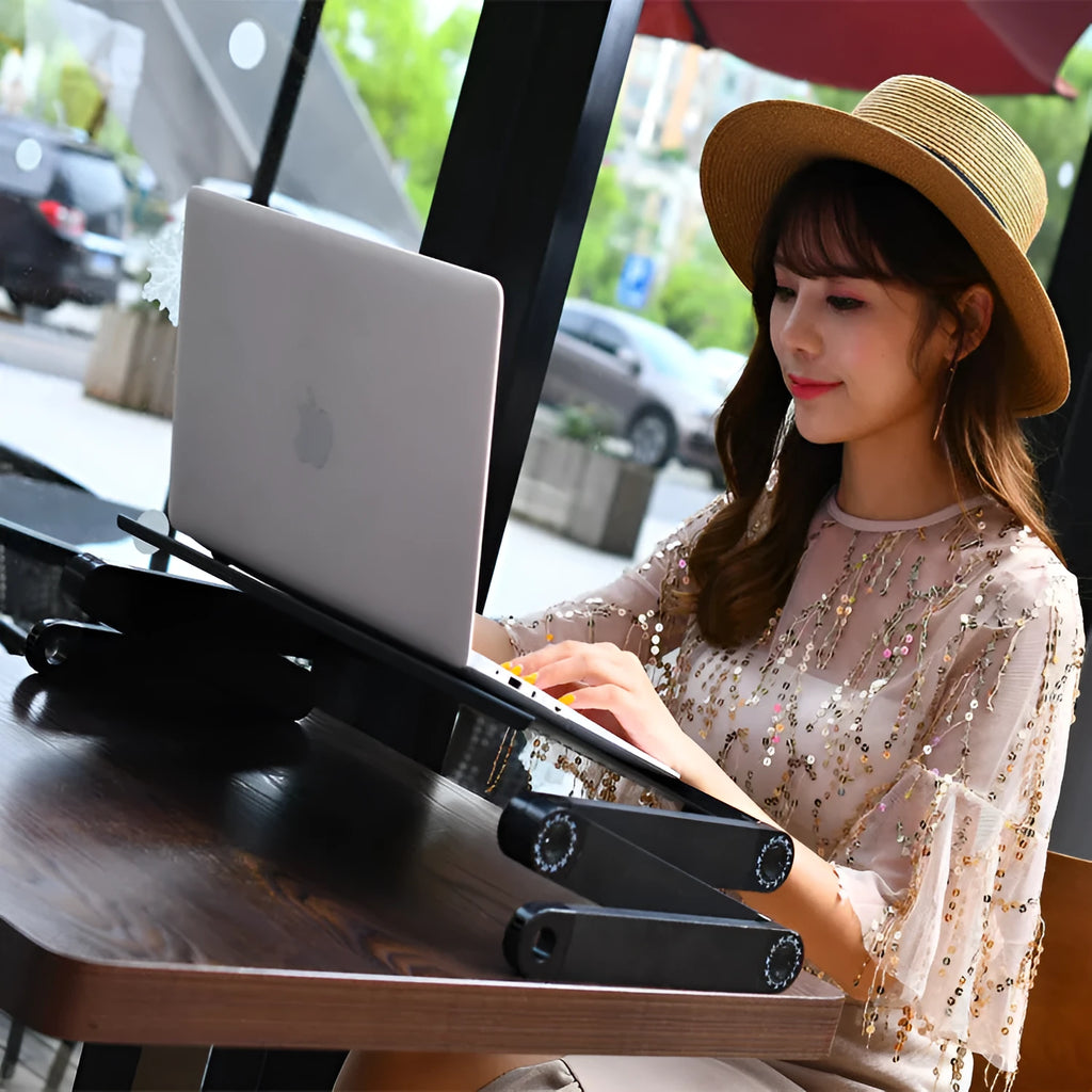 Black folding metal laptop desk with cooling holes on a sofa