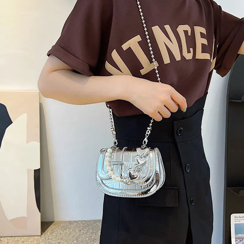 Silver laser pearl tote saddle girl mini crossbody bag with single strap on a mannequin.