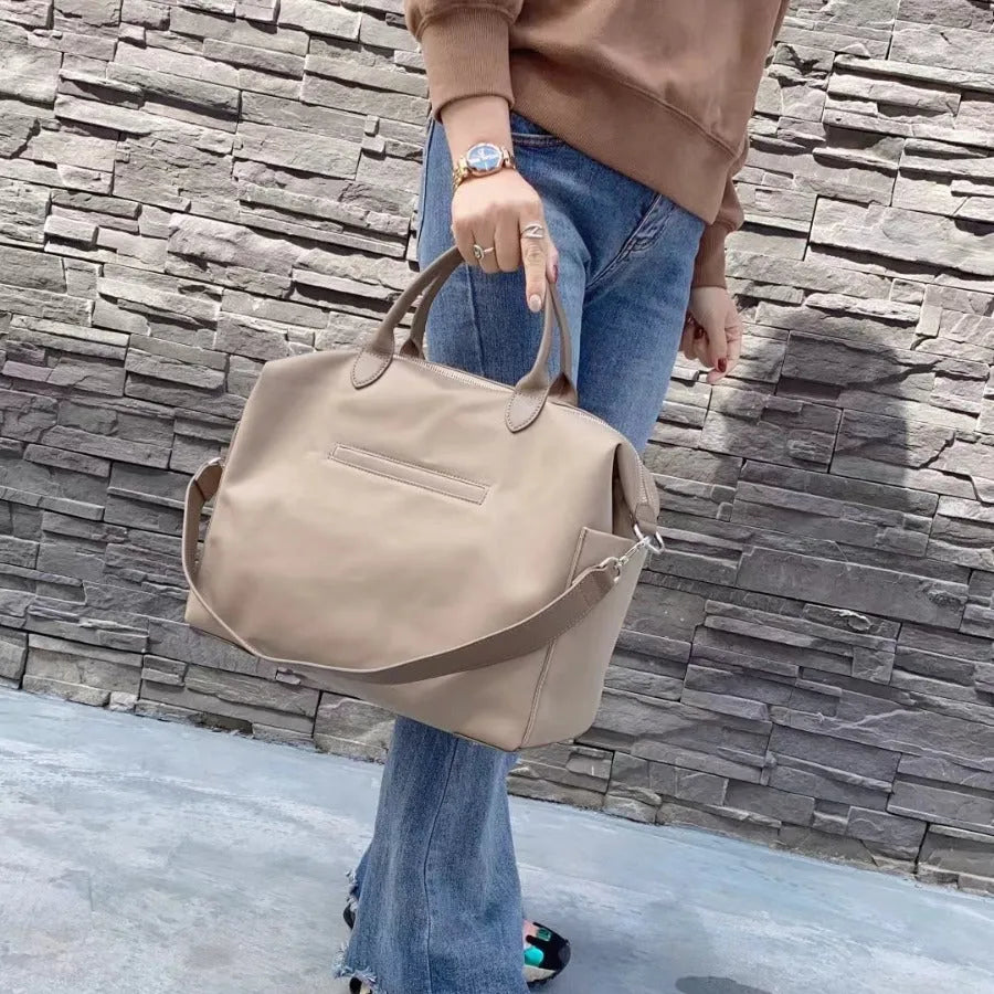 Nylon waterproof shoulder bag in black or light khaki colour measuring 35cm wide