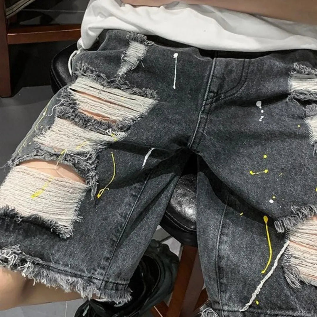 Man wearing loose-fit light blue denim shorts with a water-washed finish and distressed holes.
