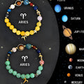 Set of twelve natural stone beaded bracelets on a table, each with charms for a different zodiac sign.