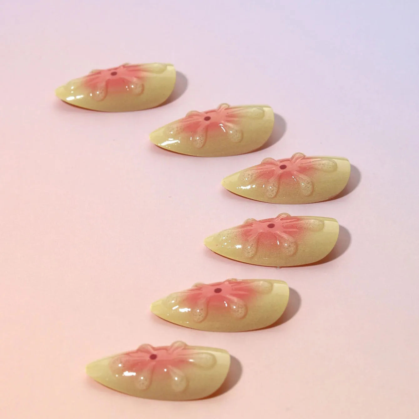 Fake nails set with white plastic armour pieces featuring raised pink and green cartoon flower designs.