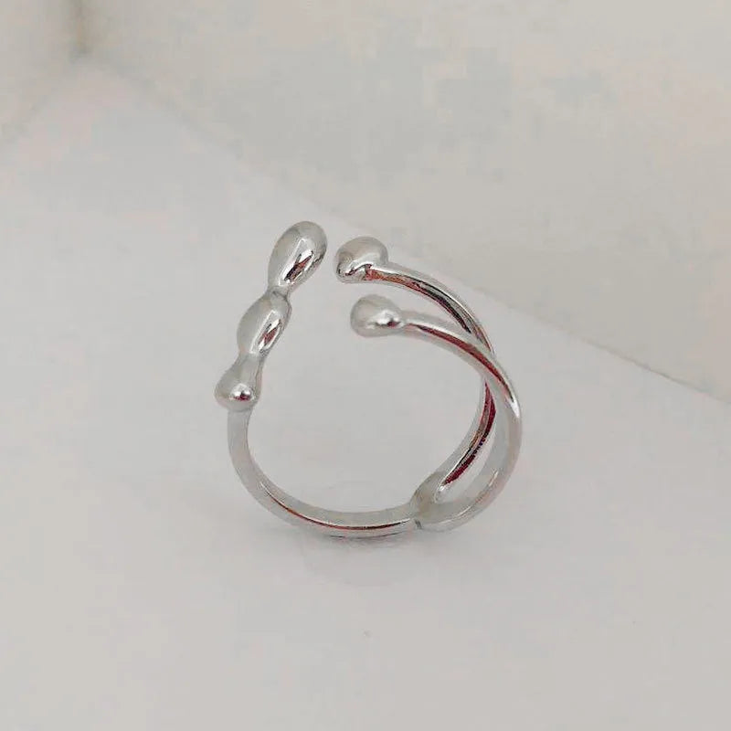 Open circle brass fashion ring with spherical beads in gold tone on a hand.