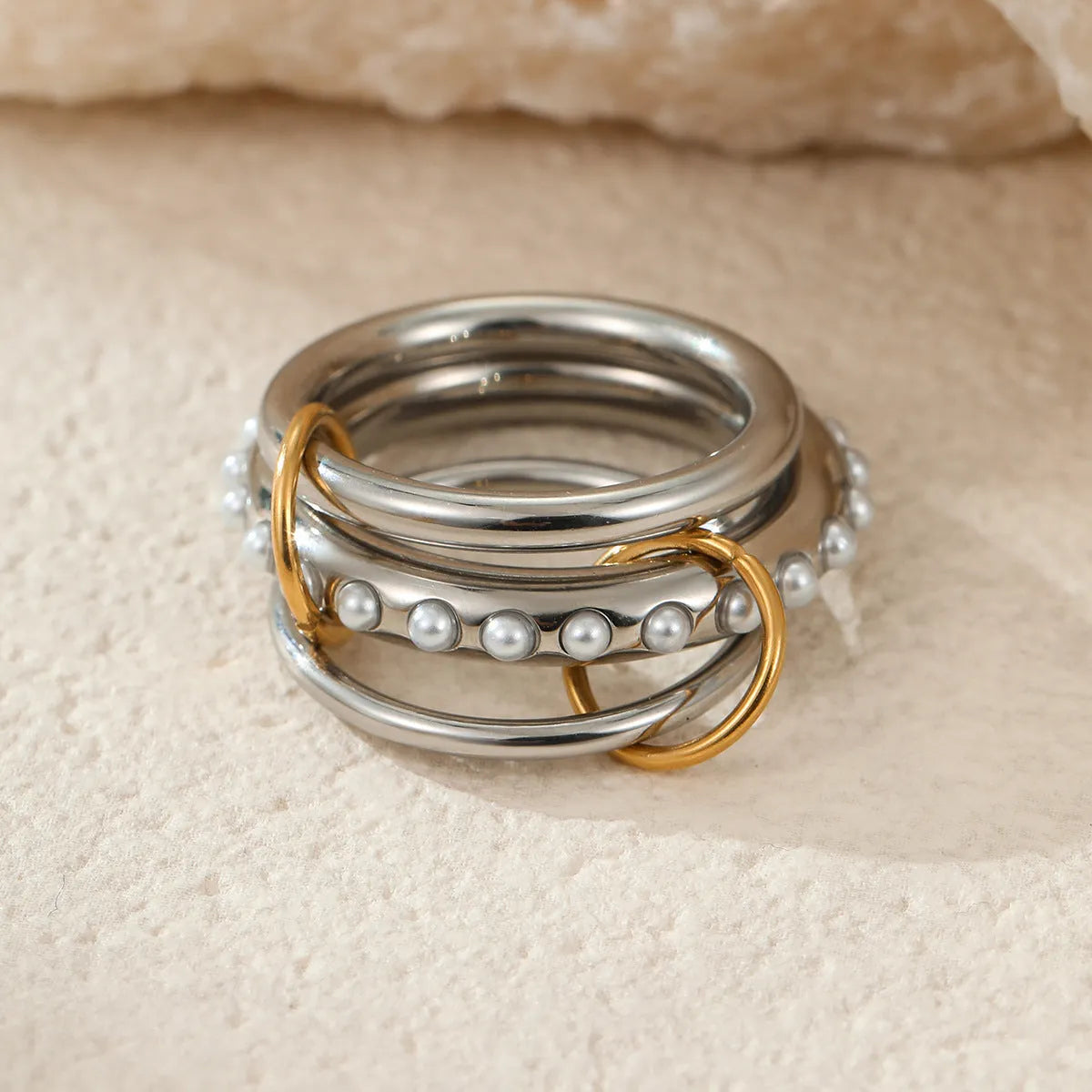 Stacked stainless steel rings with 18K gold plating in exaggerated design on woman's hand