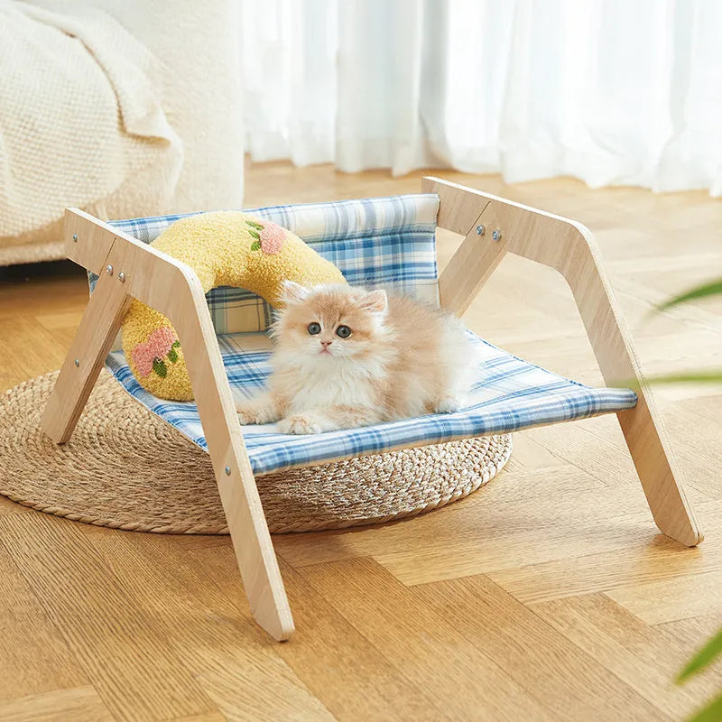 Wooden elevated cat hammock bed with a soft blue cloth sleeping mat, raised on wooden legs.