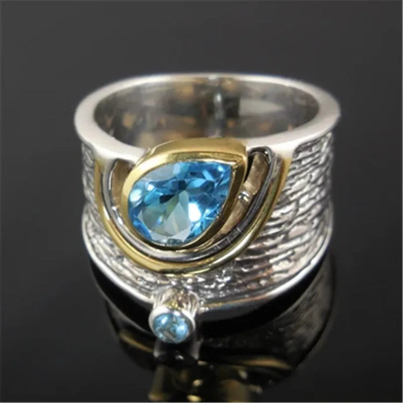Close-up of a women's blue zircon alloy ring with a drop shape and Chinese-inspired design on a hand.