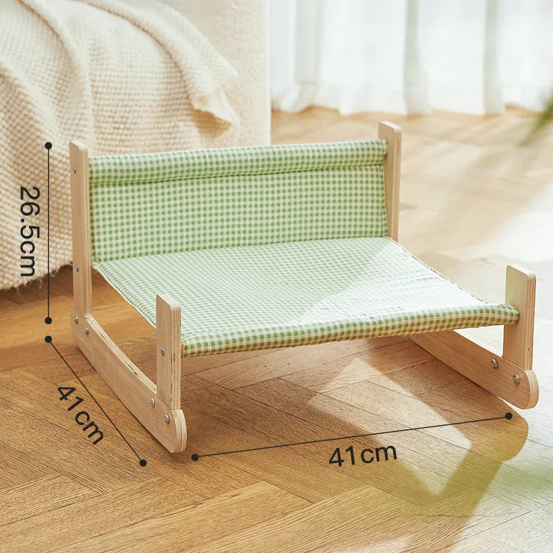 Wooden elevated cat hammock bed with a soft blue cloth sleeping mat, raised on wooden legs.