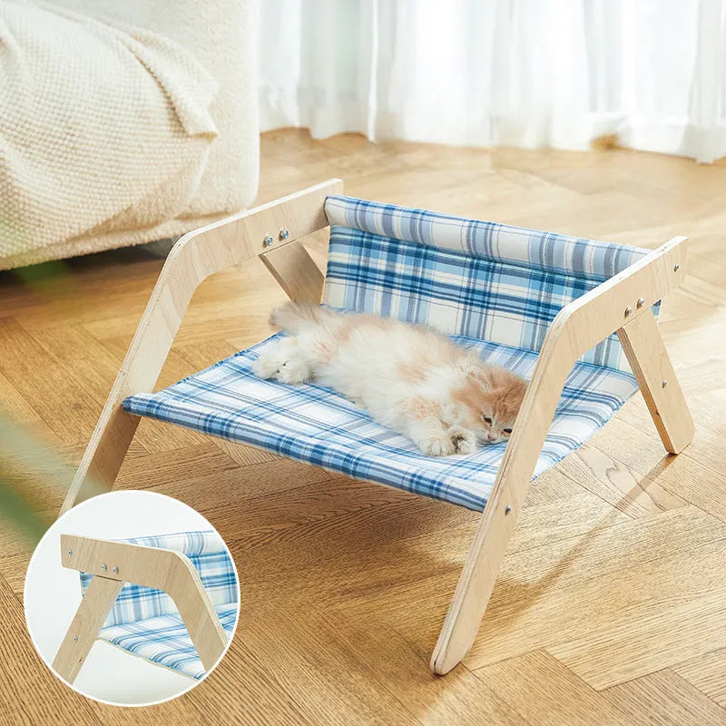 Wooden elevated cat hammock bed with a soft blue cloth sleeping mat, raised on wooden legs.