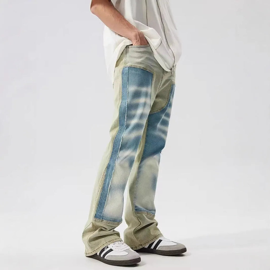 Retro blue and yellow patchwork jeans with splash-ink damaged design on a mid-waist fit.