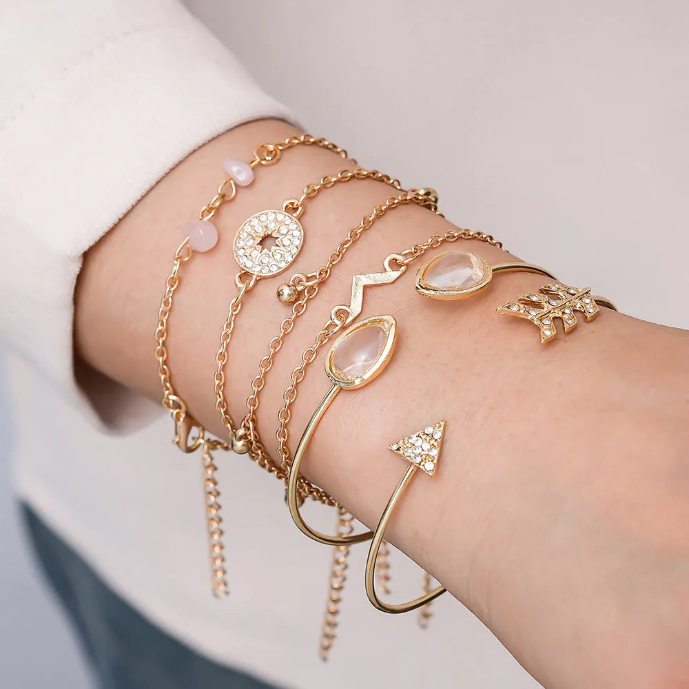 Gold-coloured women's bracelet set with six charms: arrow, water drop, and V shapes.