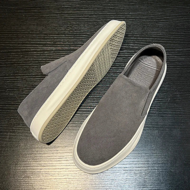Men's grey slip-on casual shoes with round toe, mid-heel, and visible stitching on a rubber sole.