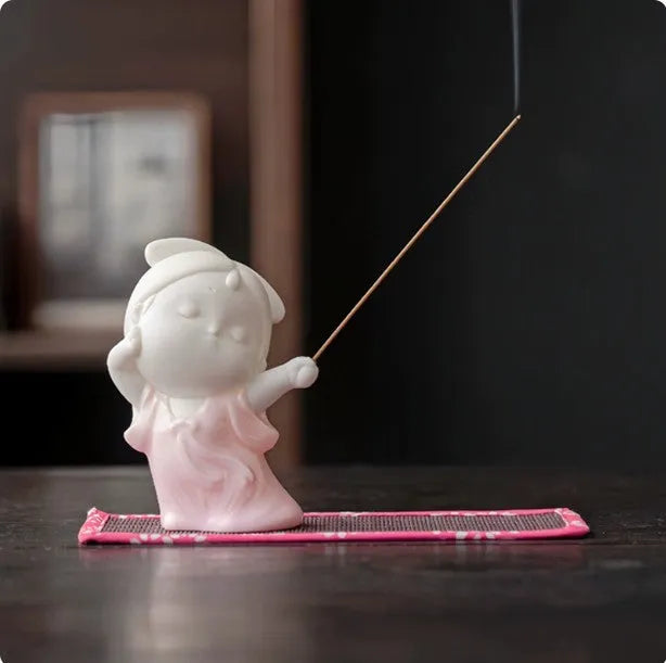 Ceramic cute female court attendant incense burner decoration in hand-painted colours on a shelf.