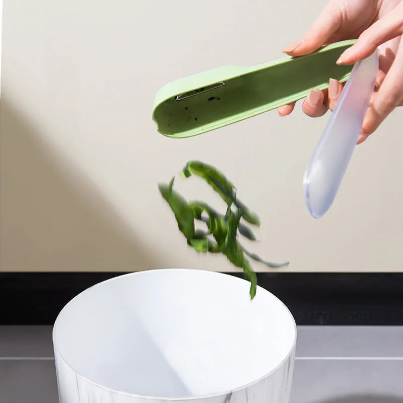 Dark green kitchen peeler with stainless steel blade stored in its tube, next to a potato.