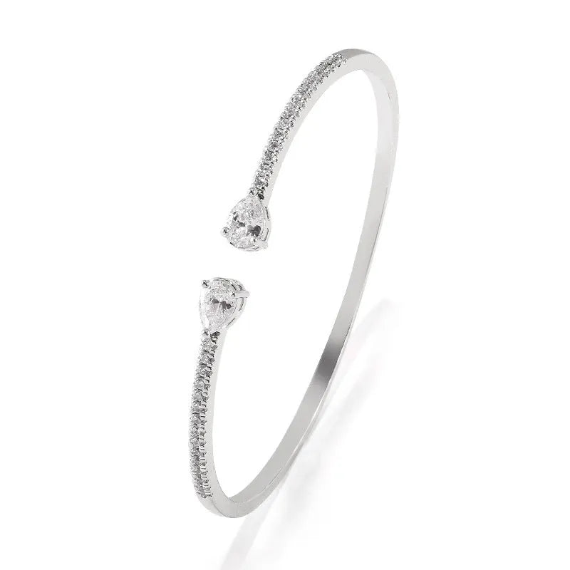 Close-up of a simple copper bracelet with inlaid blue zircon stones on a white background.