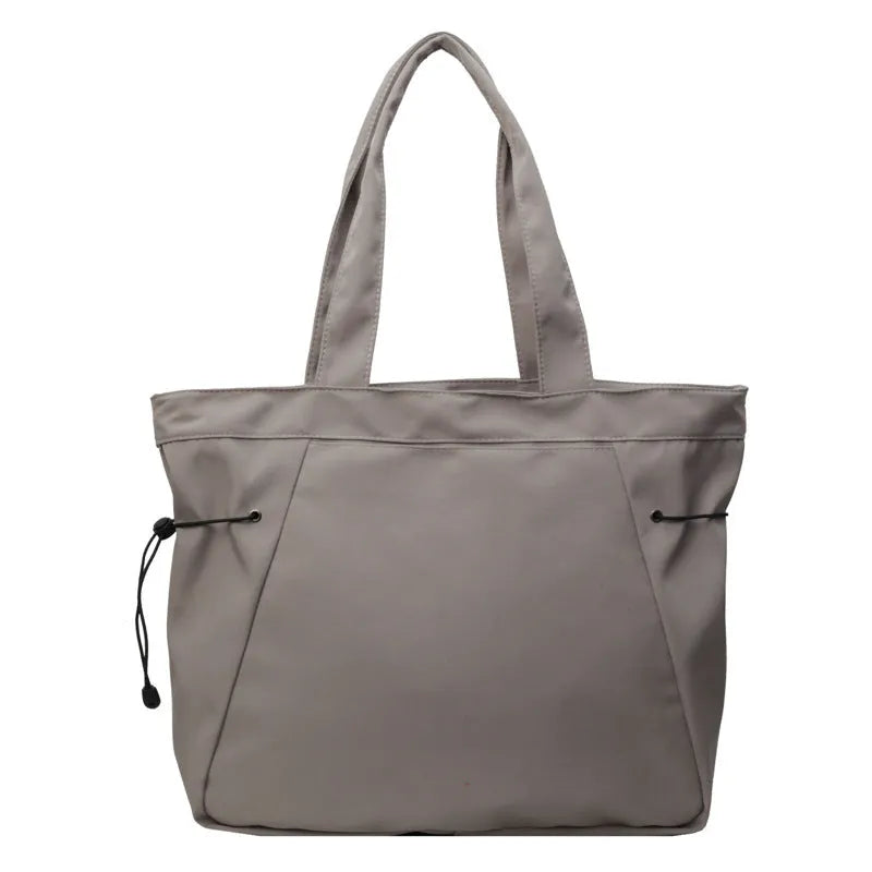 Soft Oxford cloth folding commuter tote bag shown in one of five colours: black, brown, dark grey, light grey or purple.