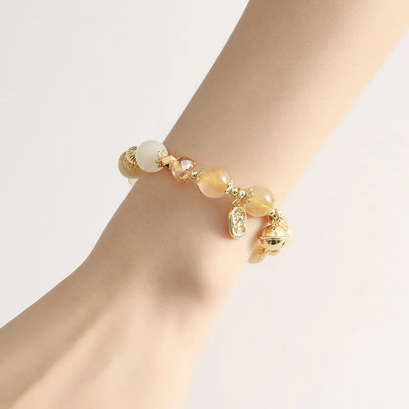 Gold electroplated bracelet with rutilated quartz crystals and a central ringing bell charm
