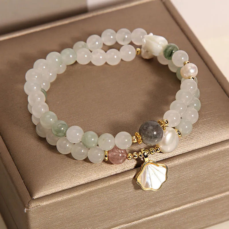 Women's crystal bracelet with a carved jade shell ginkgo leaf pendant on a gold-plated setting.