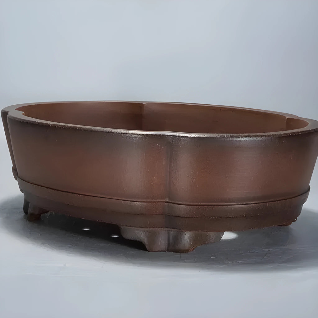 A large, simple purple clay bonsai pot on a table, suitable for indoor plants.