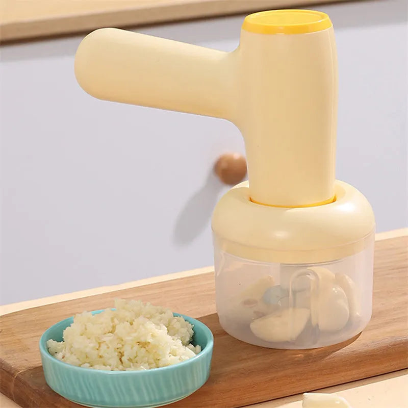 Beige electric garlic chopper with USB charging cable, 250ml cup, and stainless steel blade on kitchen counter