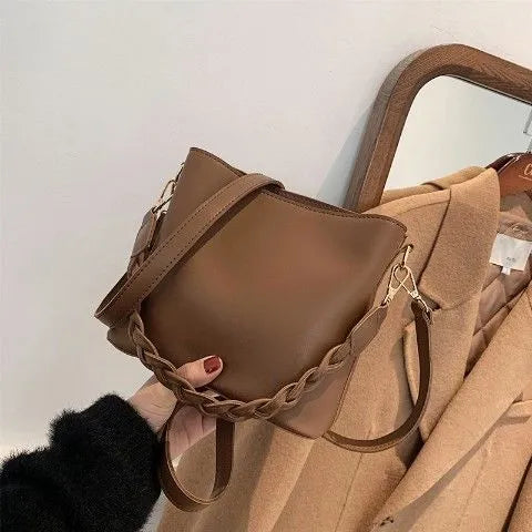 Unisex khaki PU leather crossbody bucket bag with woven texture and one shoulder strap.