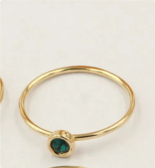 DIY knuckle ring craft kit showing 14K gold-plated ring base and green, blue, dark red, and white zircon accents.