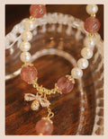 Women's handmade strawberry quartz and crystal bracelet with a decorative bow on a string of beads.