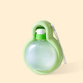 Green portable dog travel cup with pull-out bowl and handle, shown next to a backpack.
