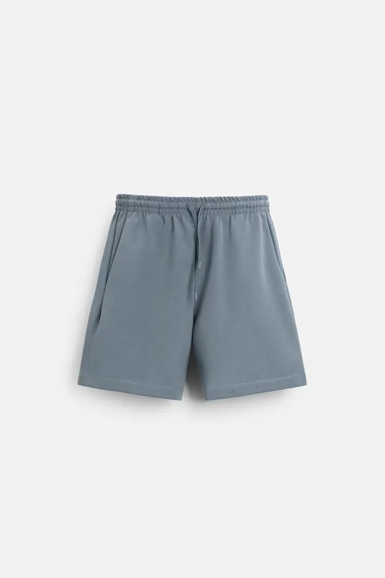 Man wearing a loose fit blue short sleeve t-shirt and matching blue shorts from a polyester two-piece set.