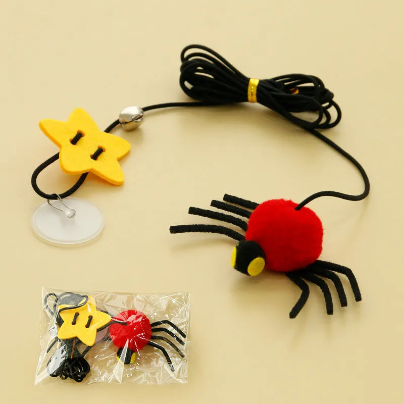 Red hanging cat toy with feather wand, bells, and spider on elastic rope, mounted on a door.