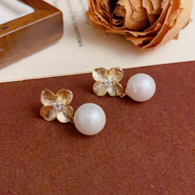 Pair of gold-plated copper earrings with metal petal design and faux pearl accents for women