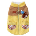 Small dog wearing a blue fleece jacket with bear embroidery and plaid pockets