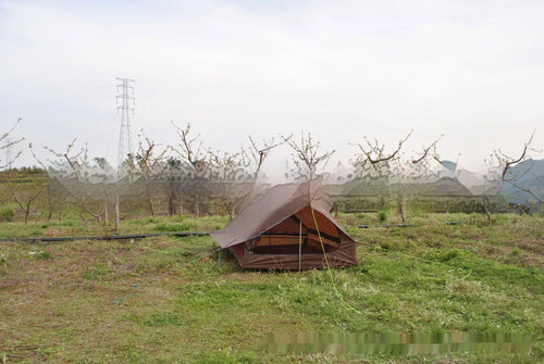 Brown or white A-frame pole-free cabin tent erected with hiking cane supports