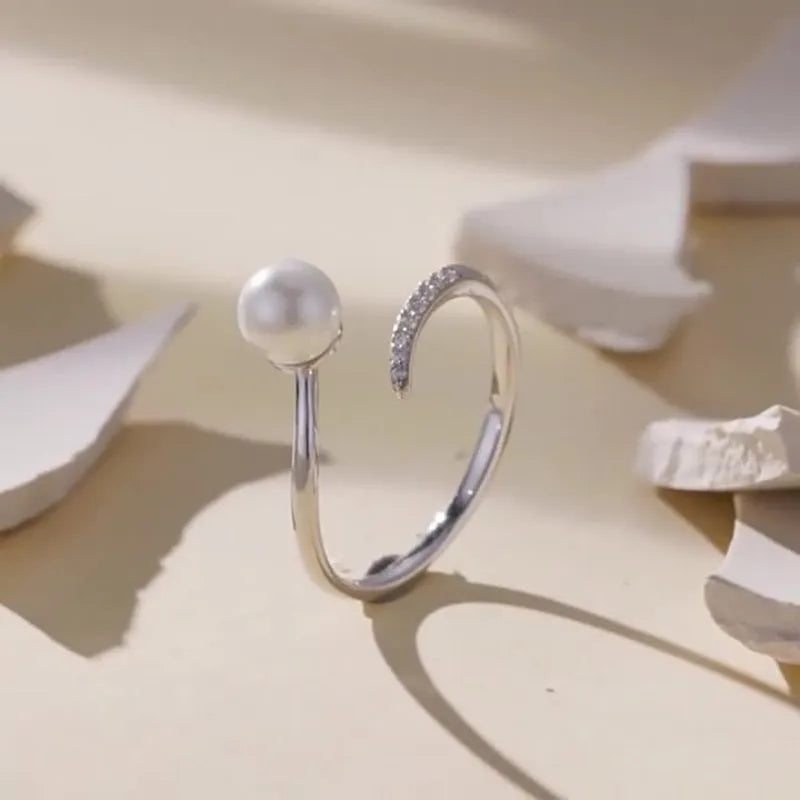 Silver adjustable ring with shell pearls showing open loop design for size adjustment