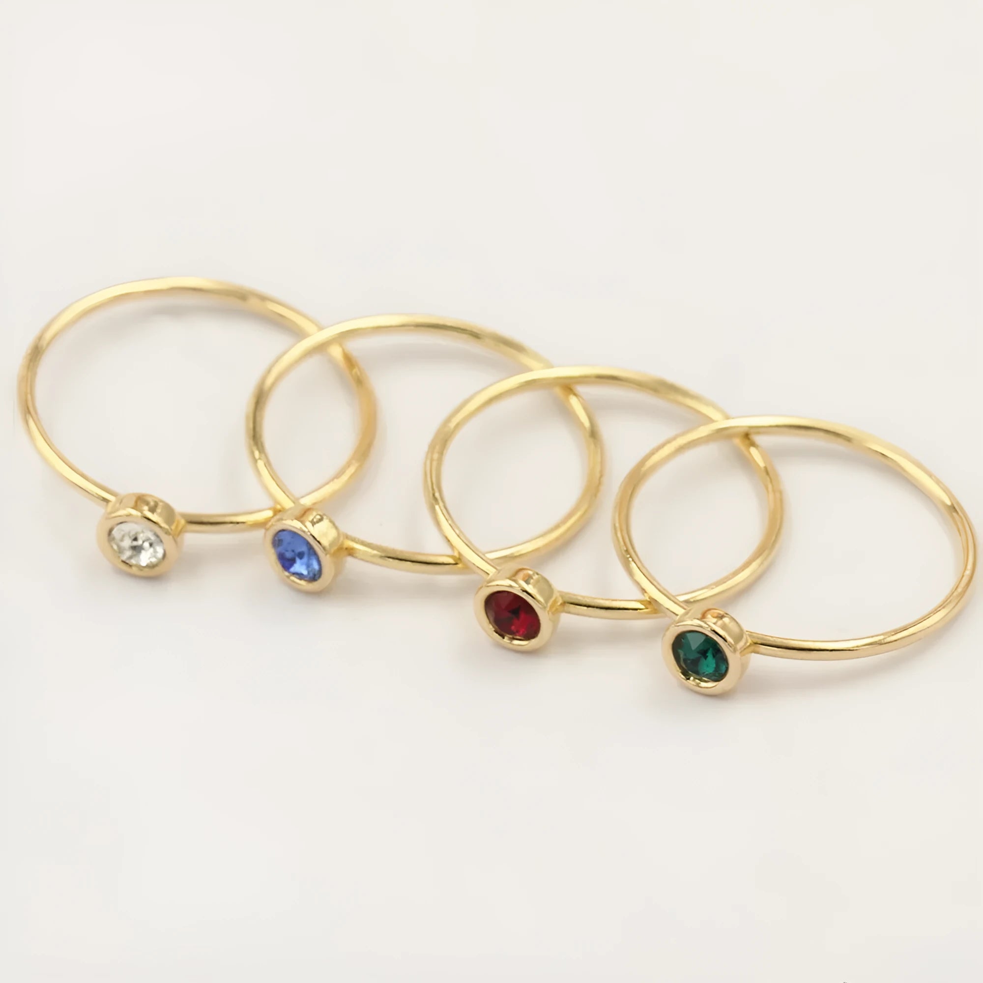DIY knuckle ring craft kit showing 14K gold-plated ring base and green, blue, dark red, and white zircon accents.