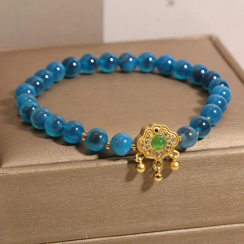 Blue agate safety lock pendant on a women's crystal bracelet with alloy-inlaid gemstones and rhinestones.