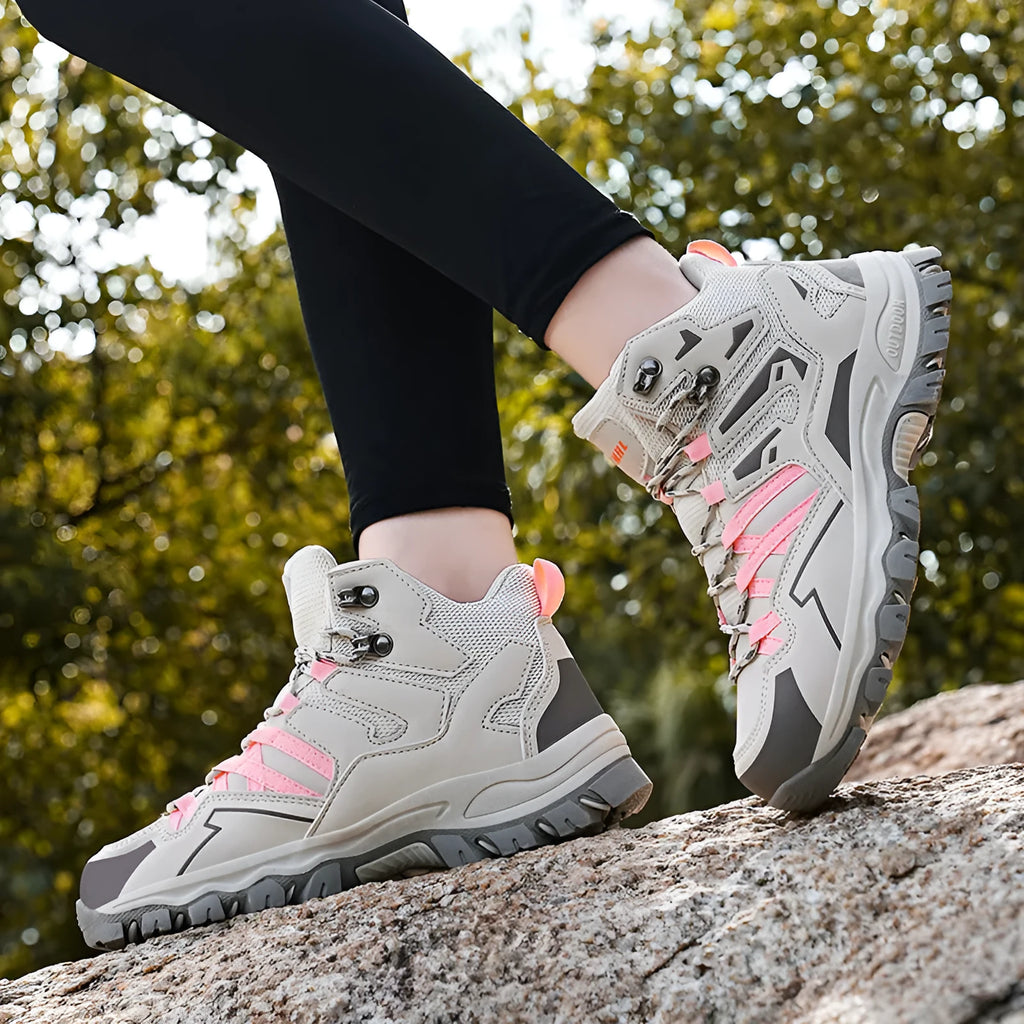 A pair of low-top hiking sneakers with a flannel upper and rubber sole, shown on a rocky mountain path.