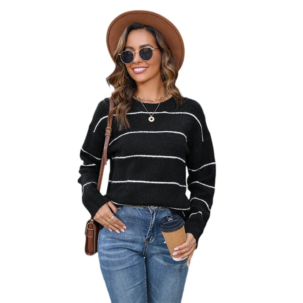 A woman's loose-fitting black and white striped pullover sweater with a round neck and regular sleeves.