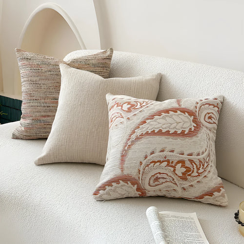 Amber paisley patterned jacquard sofa cushion cover on a sofa, showing textured fabric and plant motif.