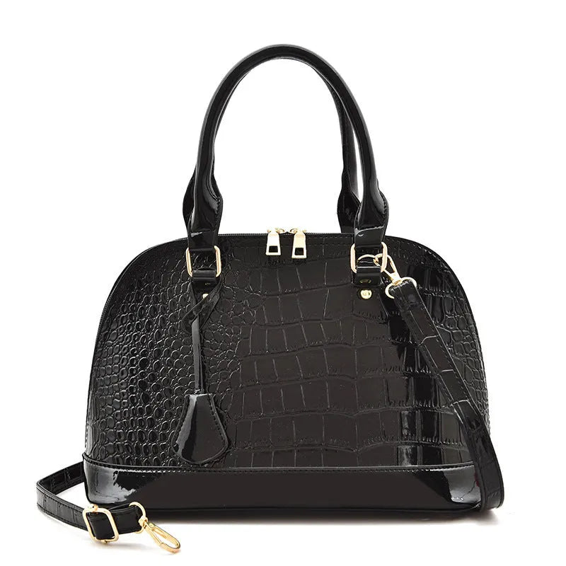 Large shiny black PU leather crossbody bag showing structured shell shape and shoulder strap.
