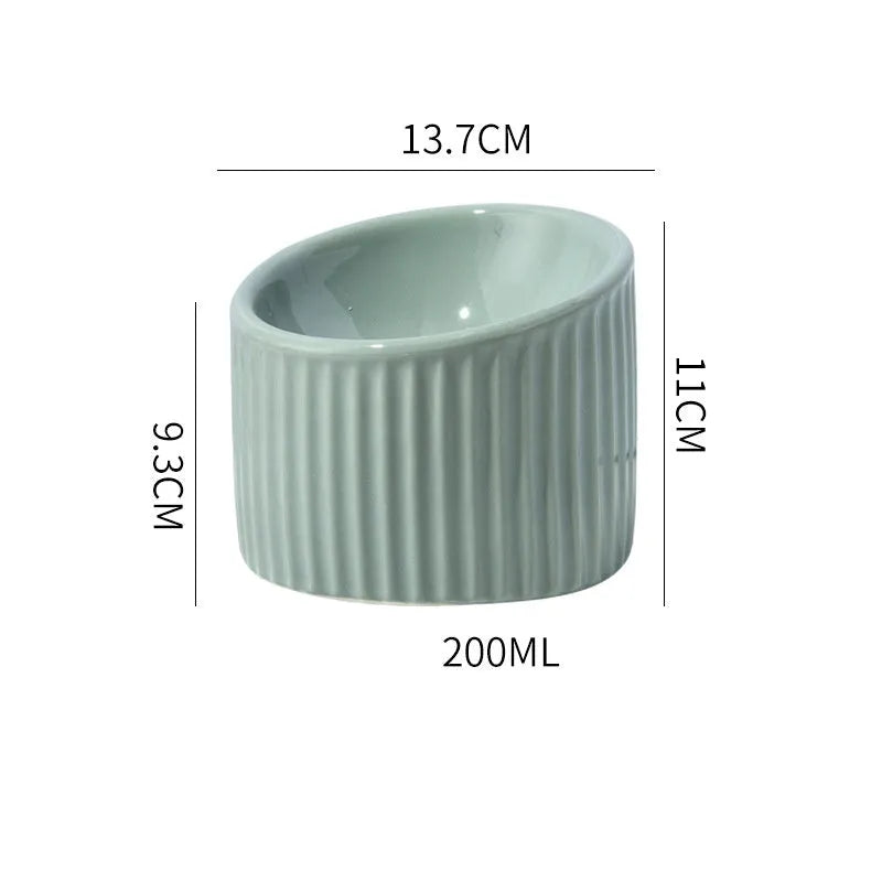 A dark green ceramic elevated cat bowl with a tilted, round design on a wooden surface.