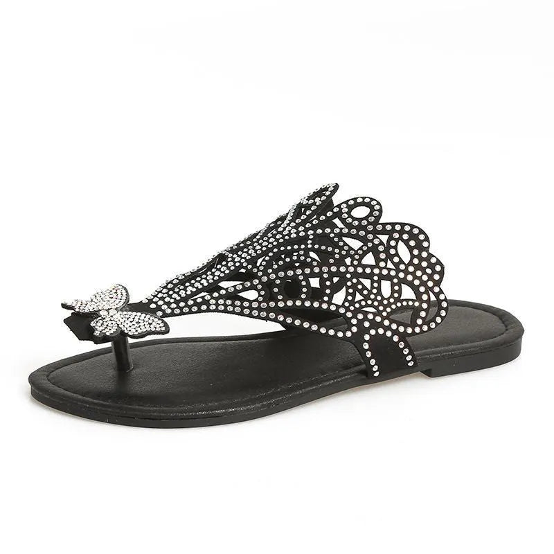 Women's black slip-on sandals with rhinestone accents and flip-toe design showing rubber sole