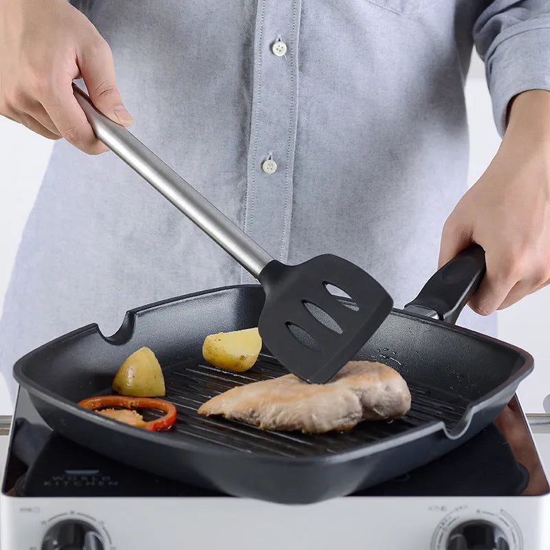 Black silicone and stainless steel kitchen spatula and spoon set, 16 pieces laid out.