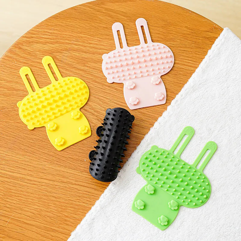 Silicone cat grooming and scratching brush with adjustable strap wrapped around a table leg.