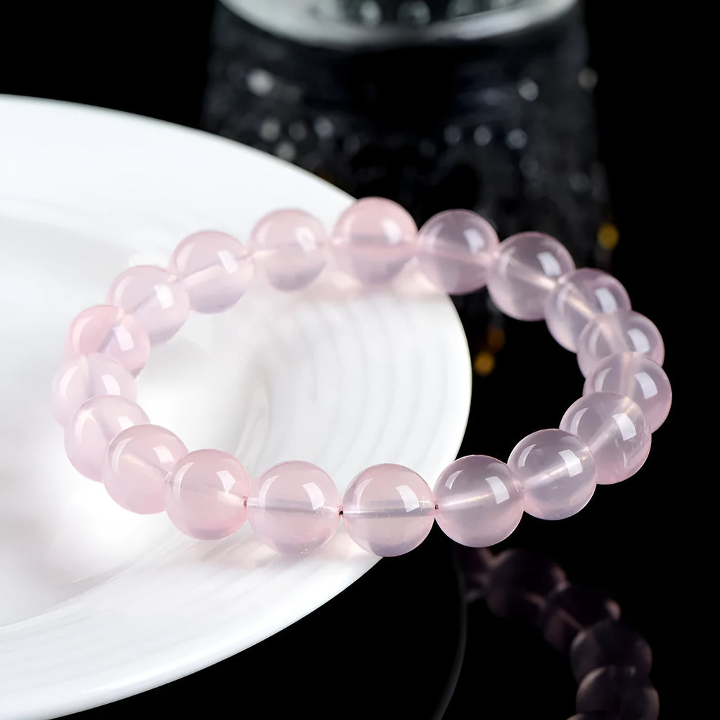 A polished natural starlight crystal bead bracelet in pink, shown as a single circle.
