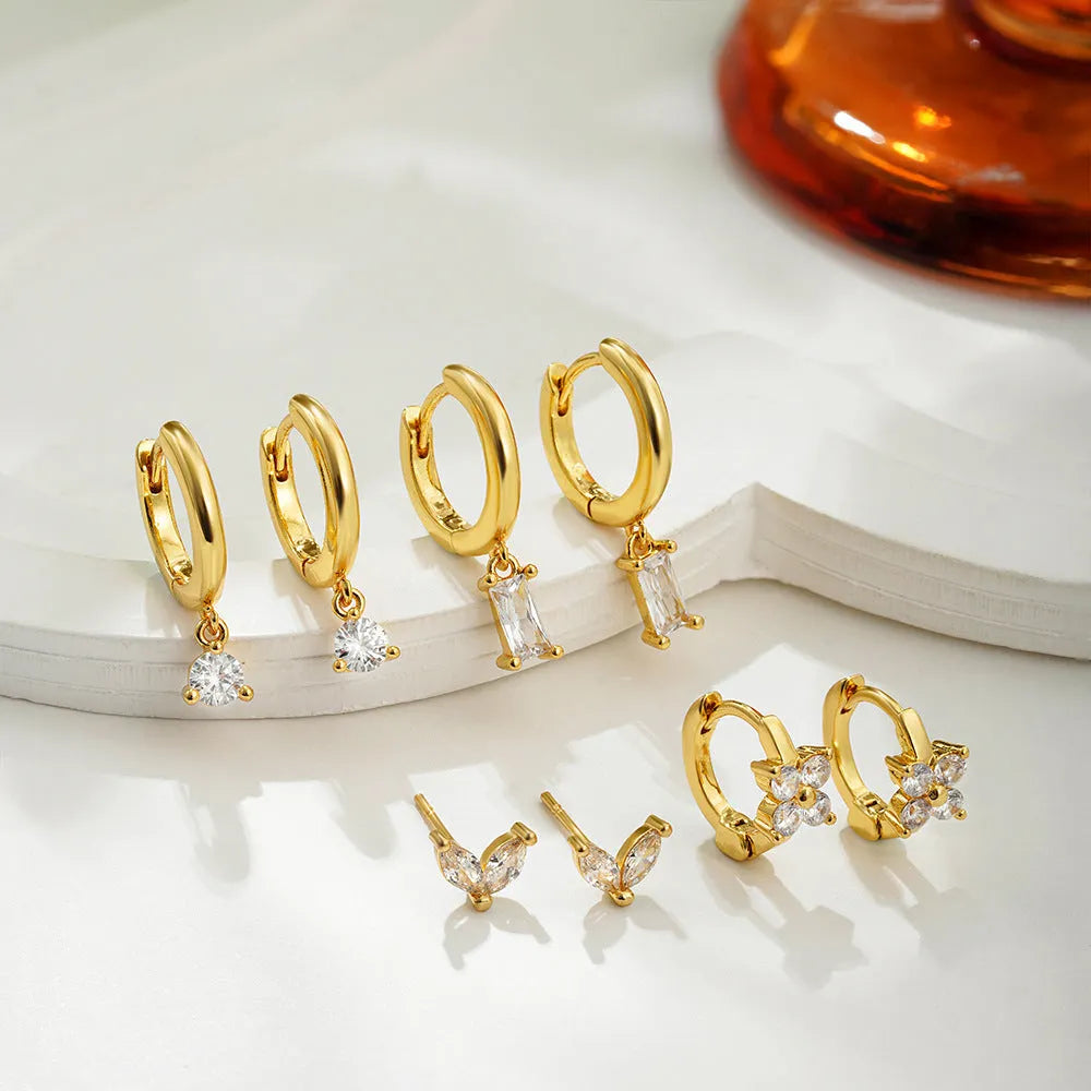 Set of four pairs of geometric copper earrings with zircon details in gold and silver colours.